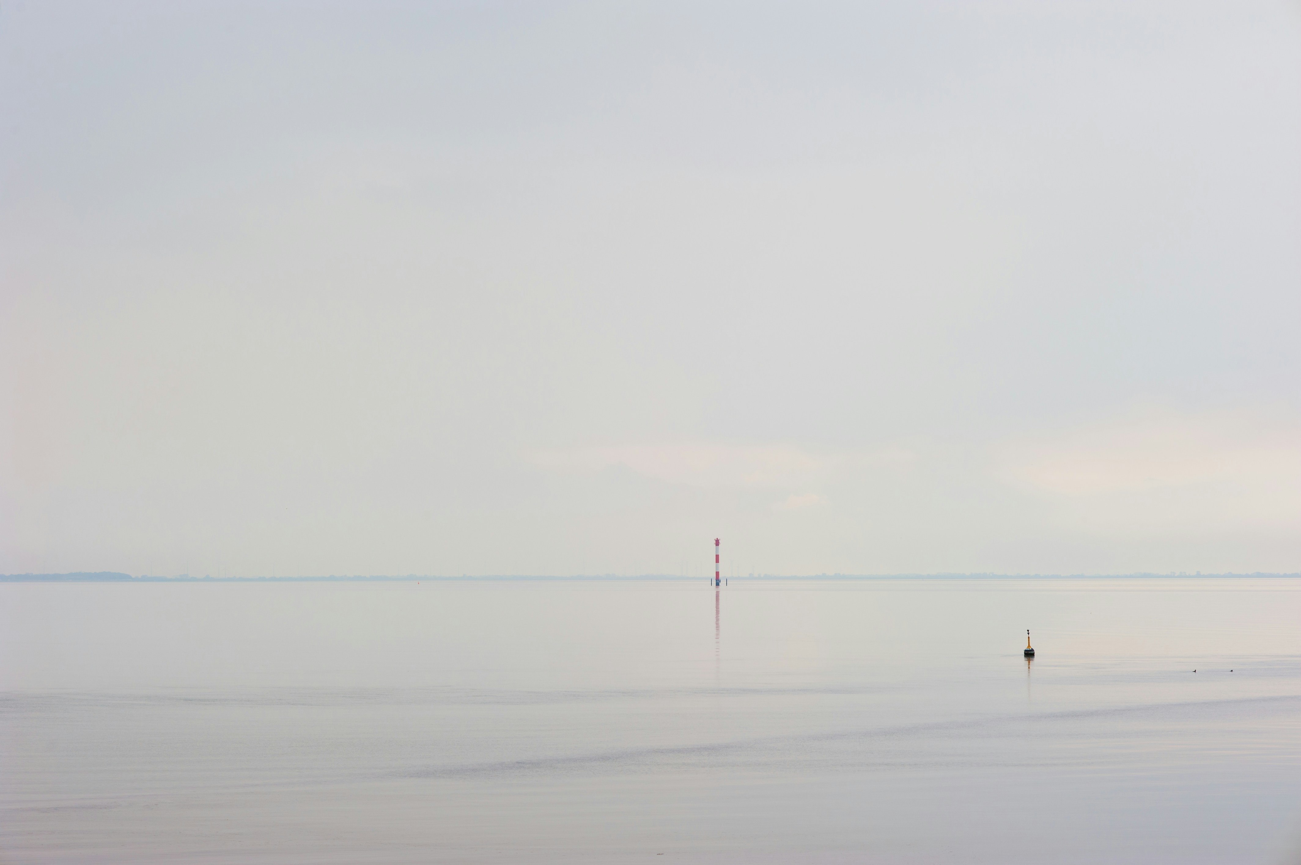 Ruhige See mit weichem Horizont und nebligem Himmel